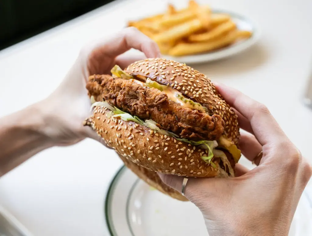 Plant-based sandwich held above a plate of fries at Stefano Diner