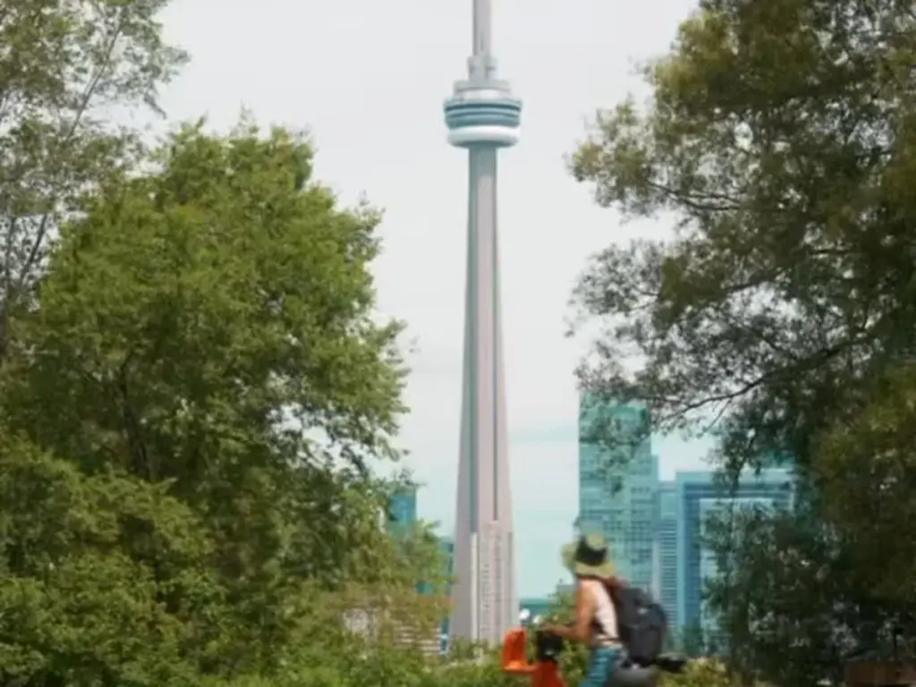 Woman walking a Bike Share Toronto bicycle with the CN Tower behind her