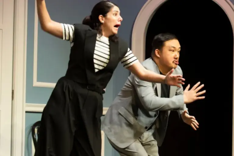 Two Second City Toronto performers acting out a lively scene onstage