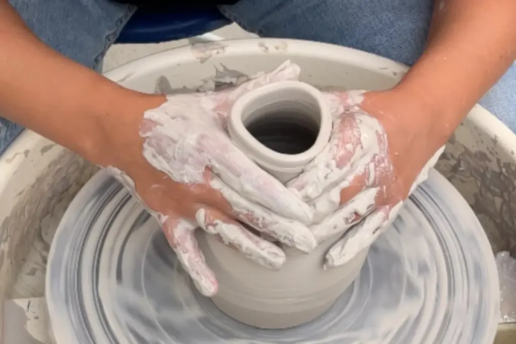 Adult pottery student shaping clay on a wheel at the Gardiner Museum