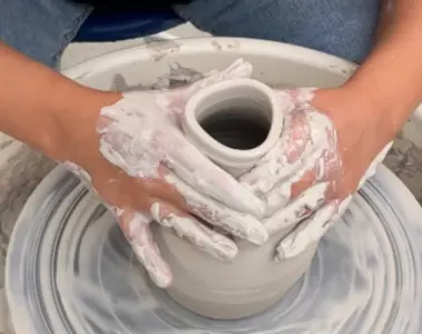 Adult pottery student shaping clay on a wheel at the Gardiner Museum
