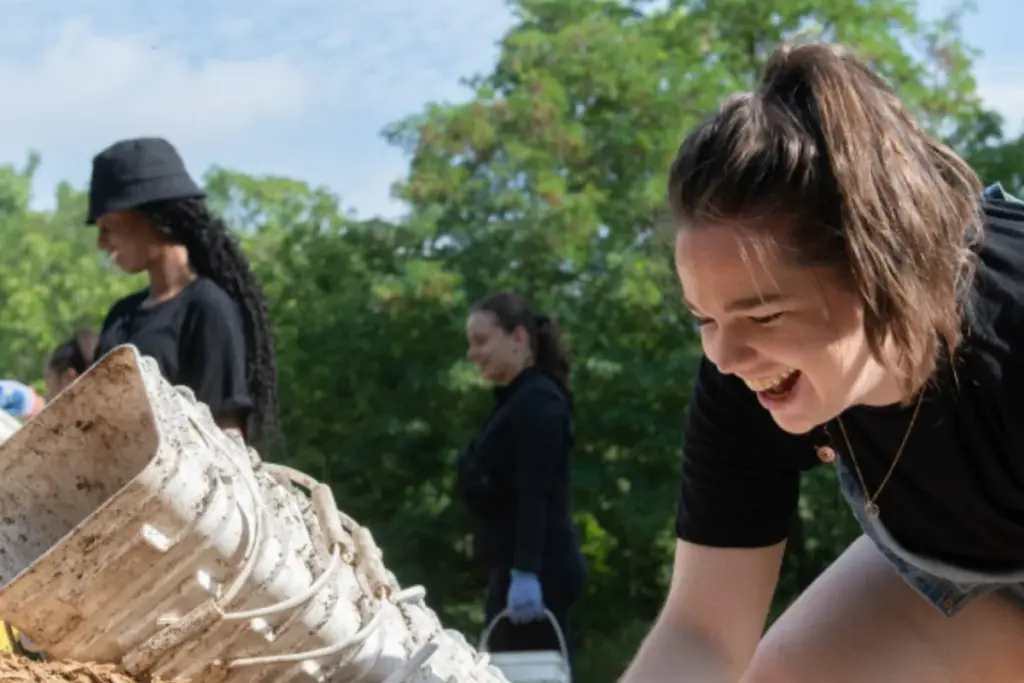 Smiling young woman spreading mulch at a Toronto community planting event