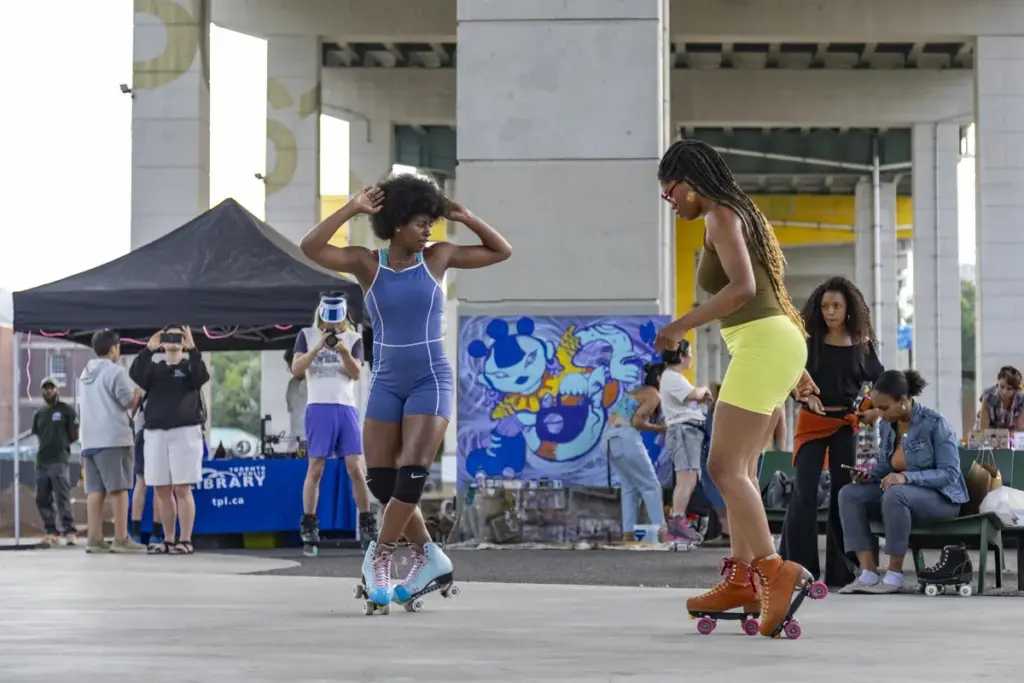 Two women roller skating and dancing together at The Bentway in Toronto