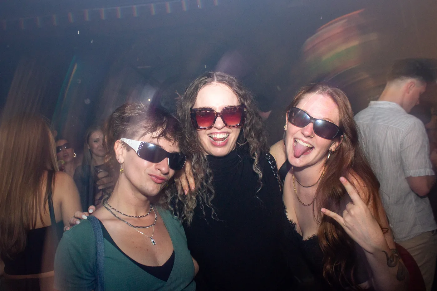 Friends smile and dance in a crowded room at Bar Cathedral.