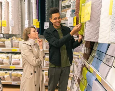 Couple comparing quilted bedding and price labels in a store