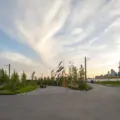 Paths and young trees in Biidaasige Park at sunset with Toronto skyline in the distance