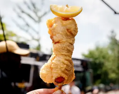 Tempura lobster tail on a stick with dill sauce and lemon