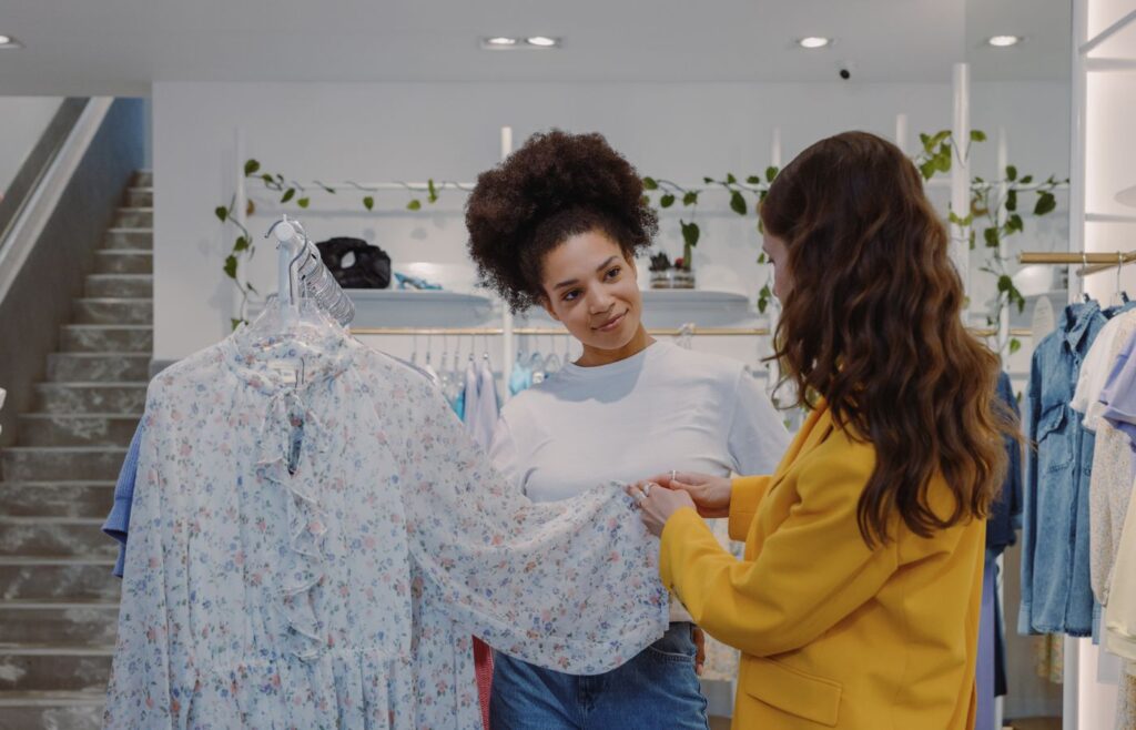 Two women looking at a floral dress inside a boutique