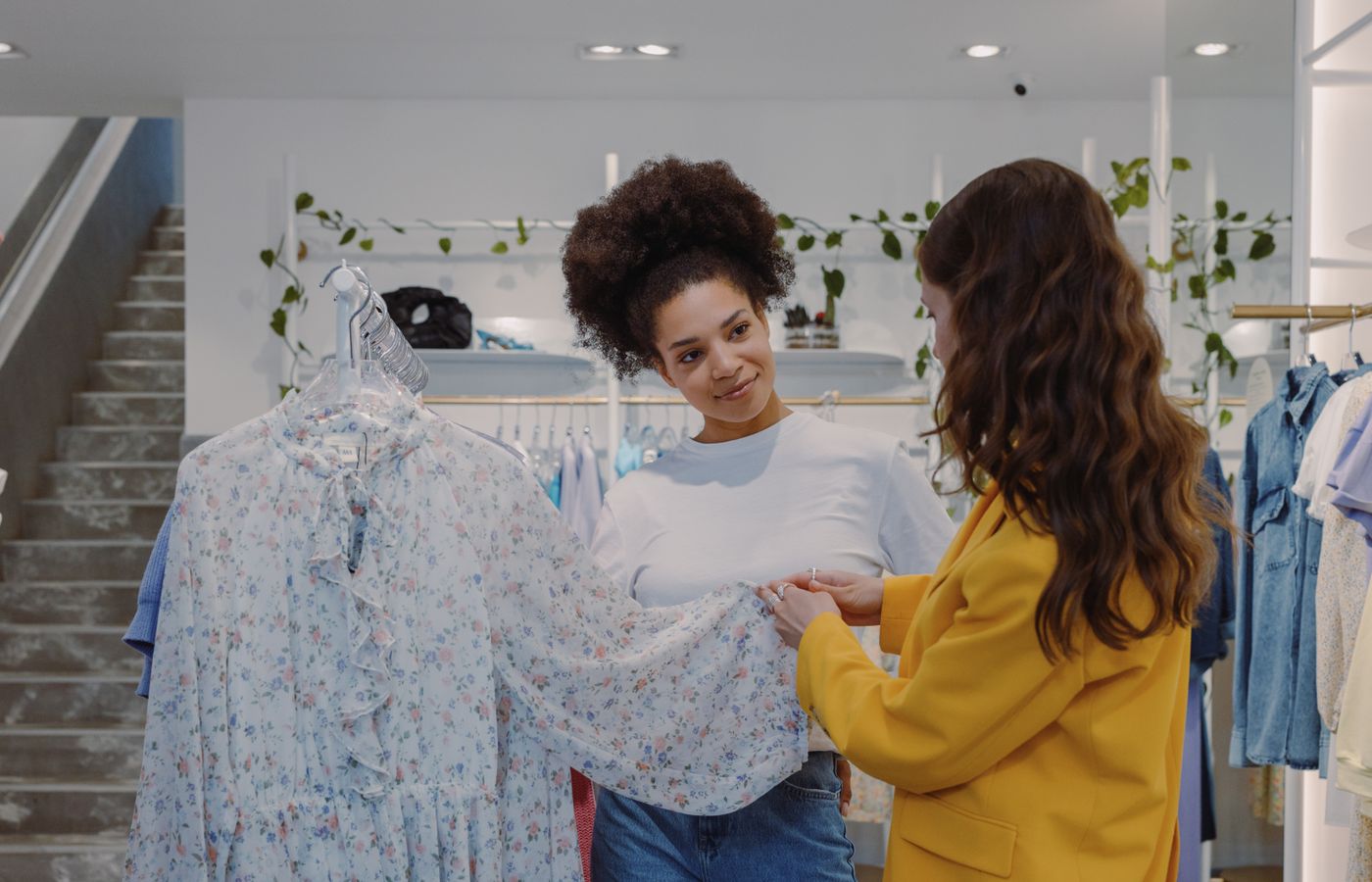 Two women looking at a floral dress inside a boutique