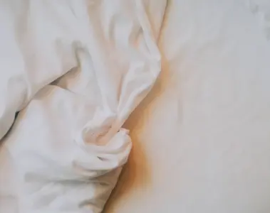 Close view of rumpled white bed sheets in warm morning light