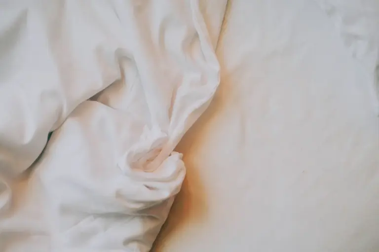 Close view of rumpled white bed sheets in warm morning light