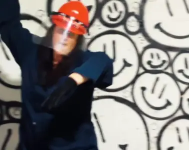 A woman in a hard hat and face shield raises a crowbar inside Chaos Studios