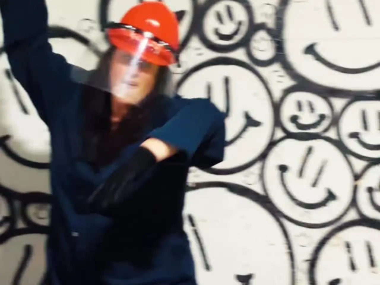 A woman in a hard hat and face shield raises a crowbar inside Chaos Studios