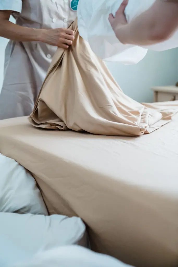 Person smoothing and checking white bed linen on a mattress