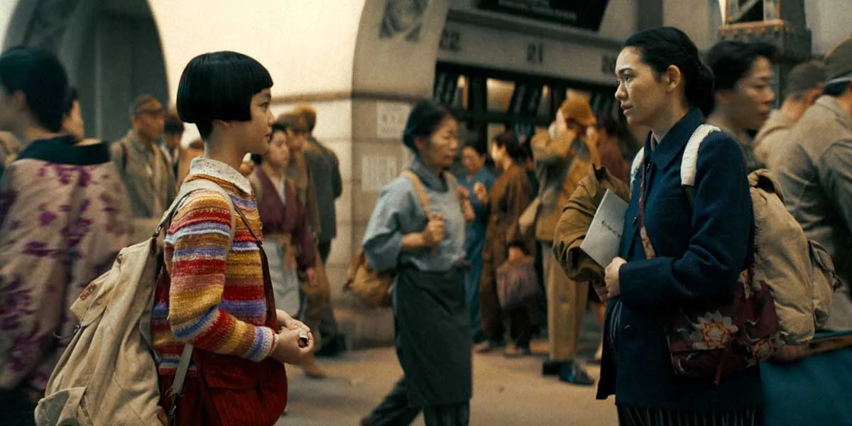 Two women face each other on a busy train platform in a scene from Children Untold