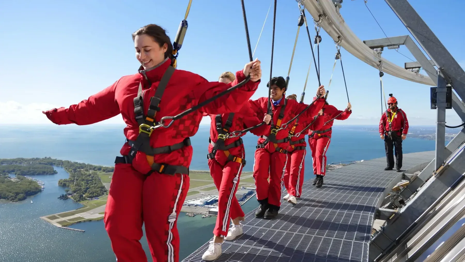 EdgeWalk participants cross the CN Tower platform in safety harnesses