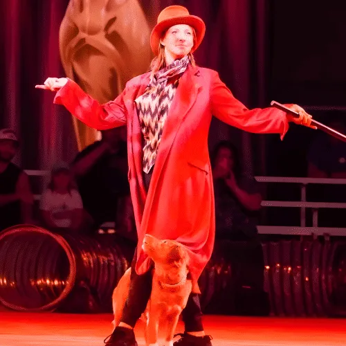 Woman in a bright red costume performing on stage with a SuperDog