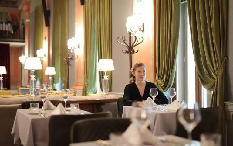 Woman seated alone at a carefully set restaurant table