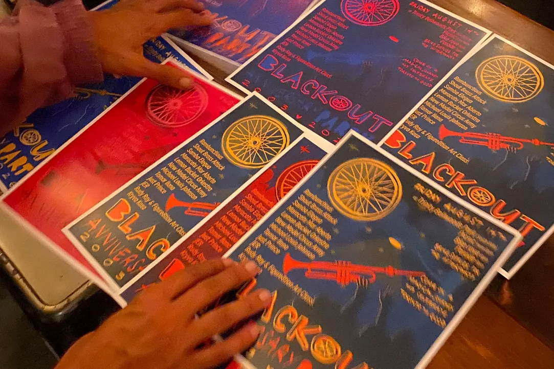 People hold colourful Blackout anniversary posters at DROM Taberna.