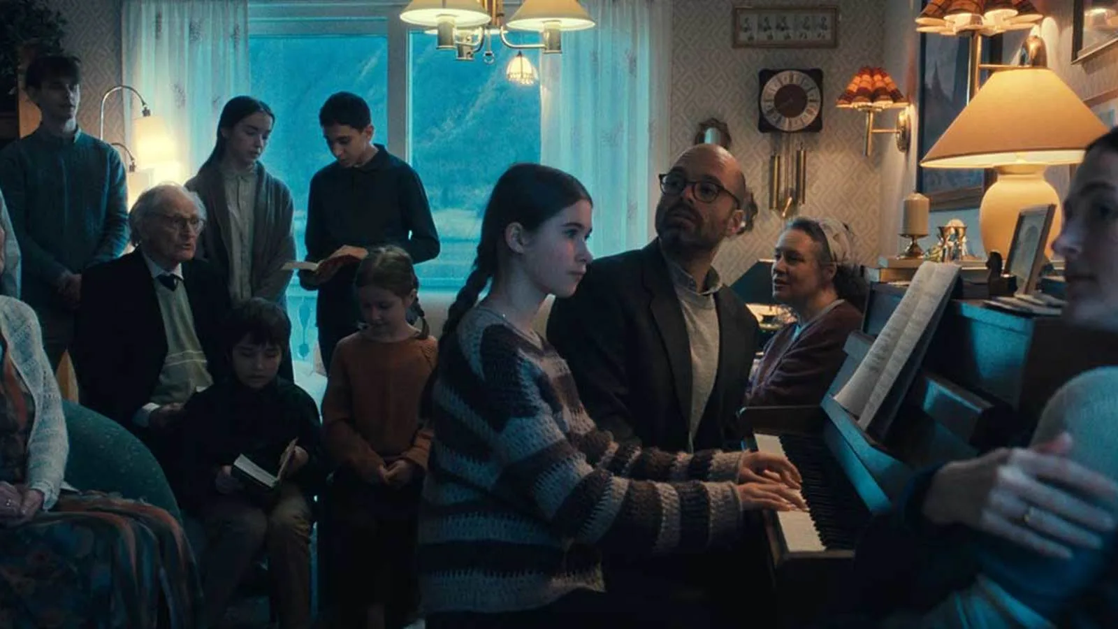 A family gathers around a piano in a scene from Fjord