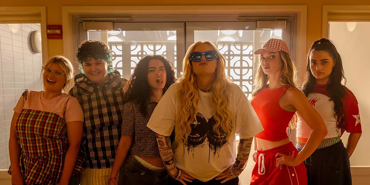 Six women sing together in a warm rehearsal room in a scene from Girl Group