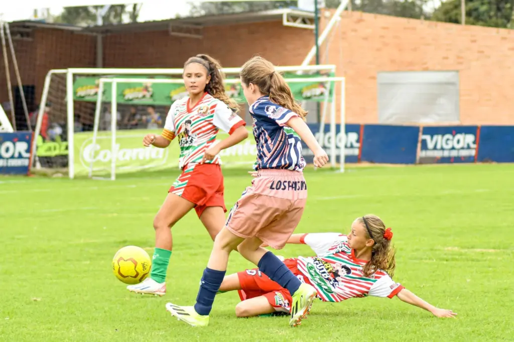 Girls playing soccer together on an outdoor field