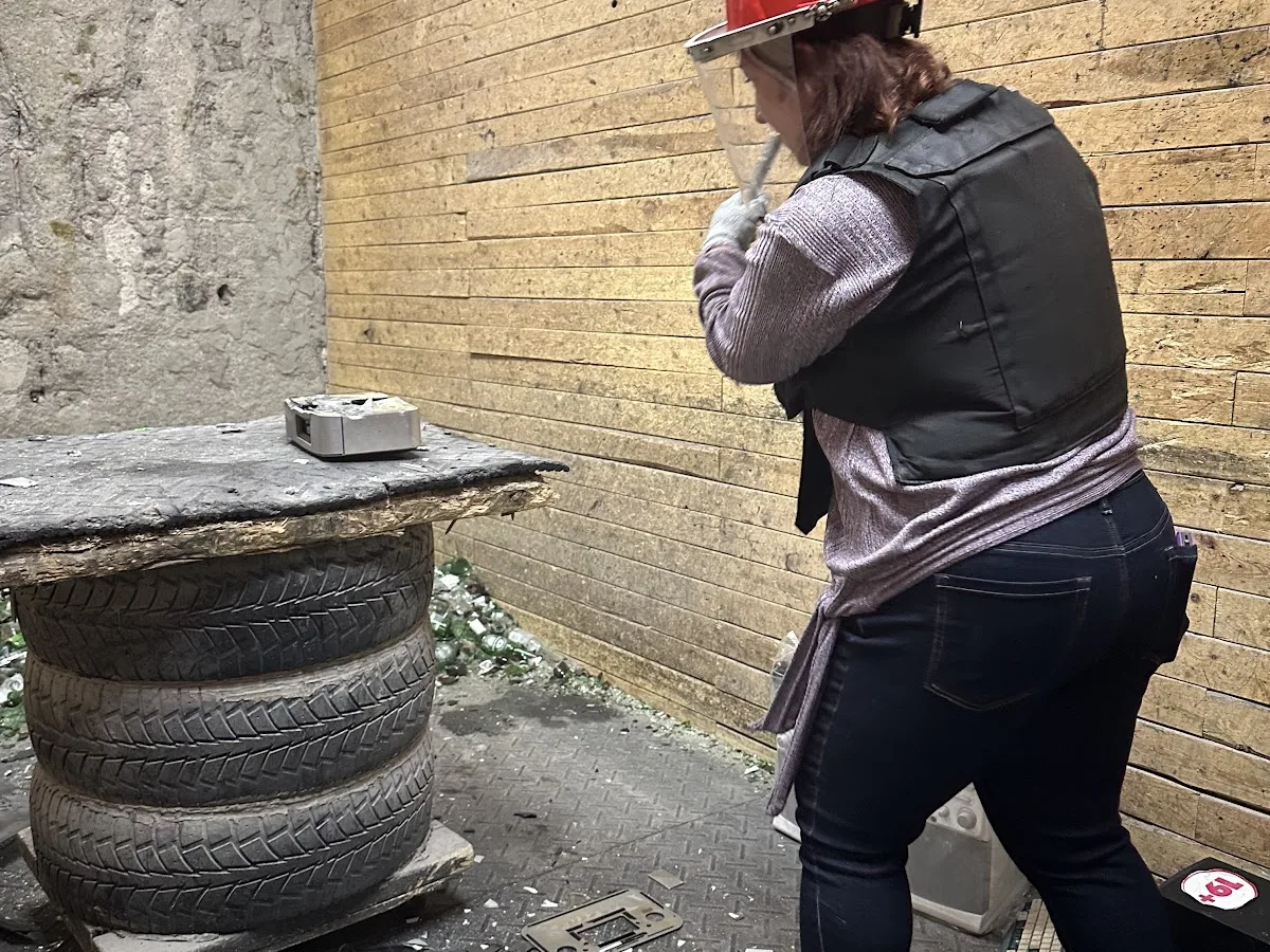 A woman in protective gear swings at an object inside Go Smash Canada