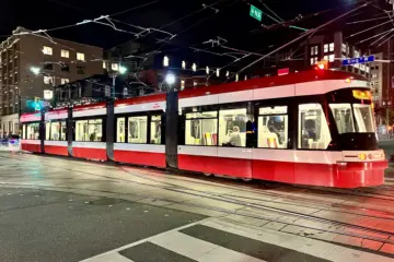 Red and white TTC streetcar at Spadina Avenue and King Street at night