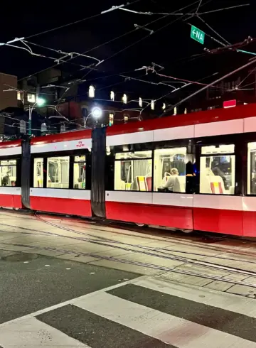 Red and white TTC streetcar at Spadina Avenue and King Street at night