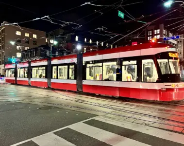 Red and white TTC streetcar at Spadina Avenue and King Street at night