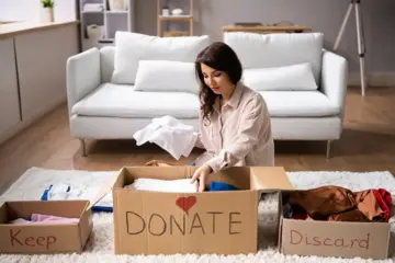 Woman sorting clothes into keep, donate and discard boxes