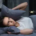 Woman covering her ears with a pillow while trying to sleep
