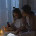 A mother and daughter reading together by flashlight during a power outage