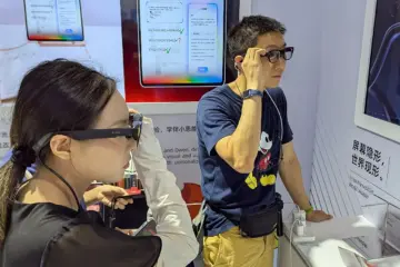 A woman and a man trying camera-equipped smart glasses at a technology exhibition