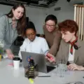 Women reviewing work together around a laptop in a bright office