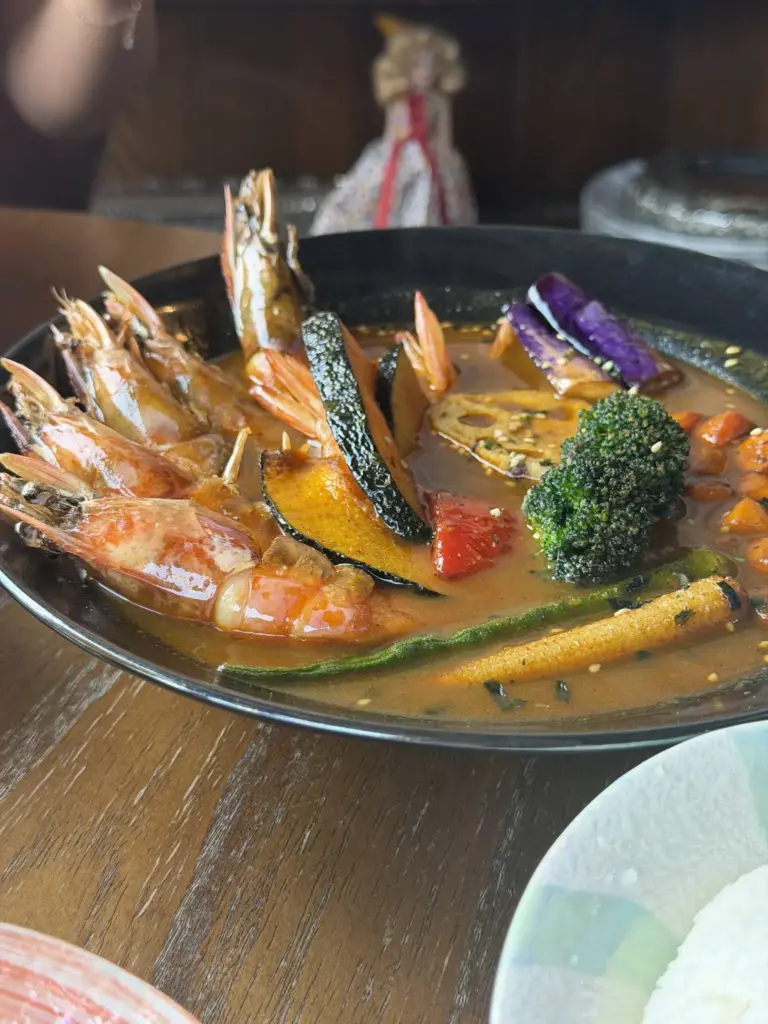 Bowl of curry soup with shrimp and vegetables at Lost in Toronto bar.