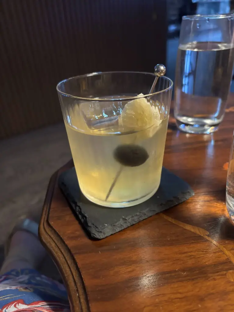 Velvet Ash cocktail with a black olive and citrus peel at Lost in Toronto bar.