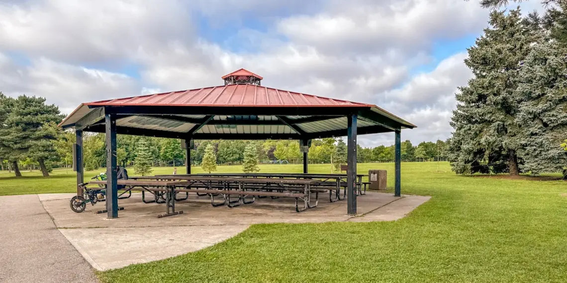 A large red-roofed picnic shelter on green parkland at Milliken Park