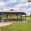 A large red-roofed picnic shelter on green parkland at Milliken Park