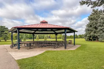 A large red-roofed picnic shelter on green parkland at Milliken Park