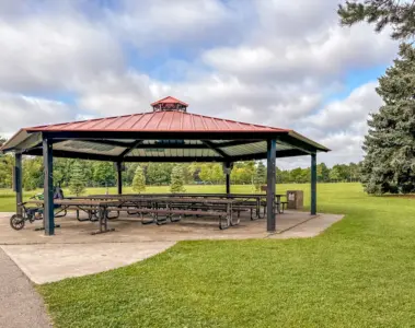 A large red-roofed picnic shelter on green parkland at Milliken Park