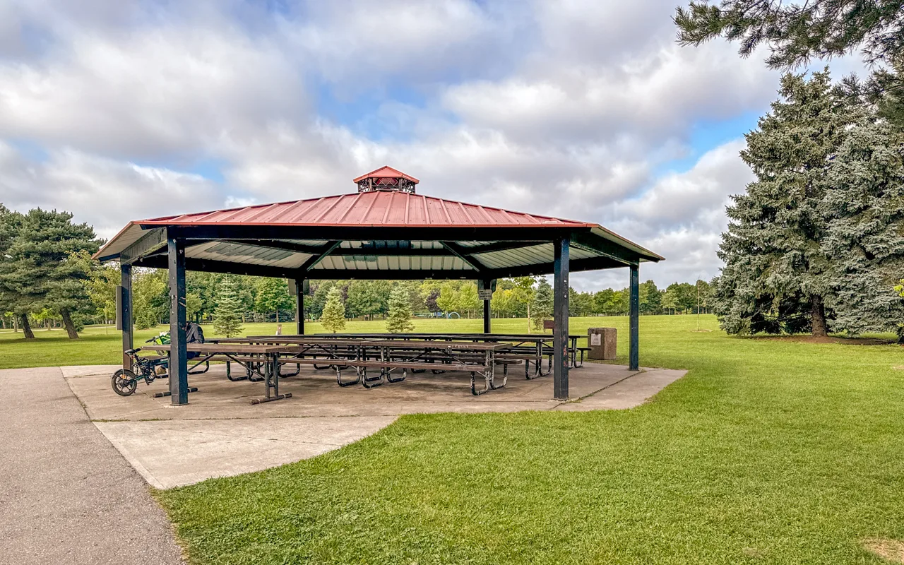 A large red-roofed picnic shelter on green parkland at Milliken Park