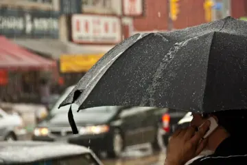 People carrying umbrellas on a rainy street in Toronto's Chinatown