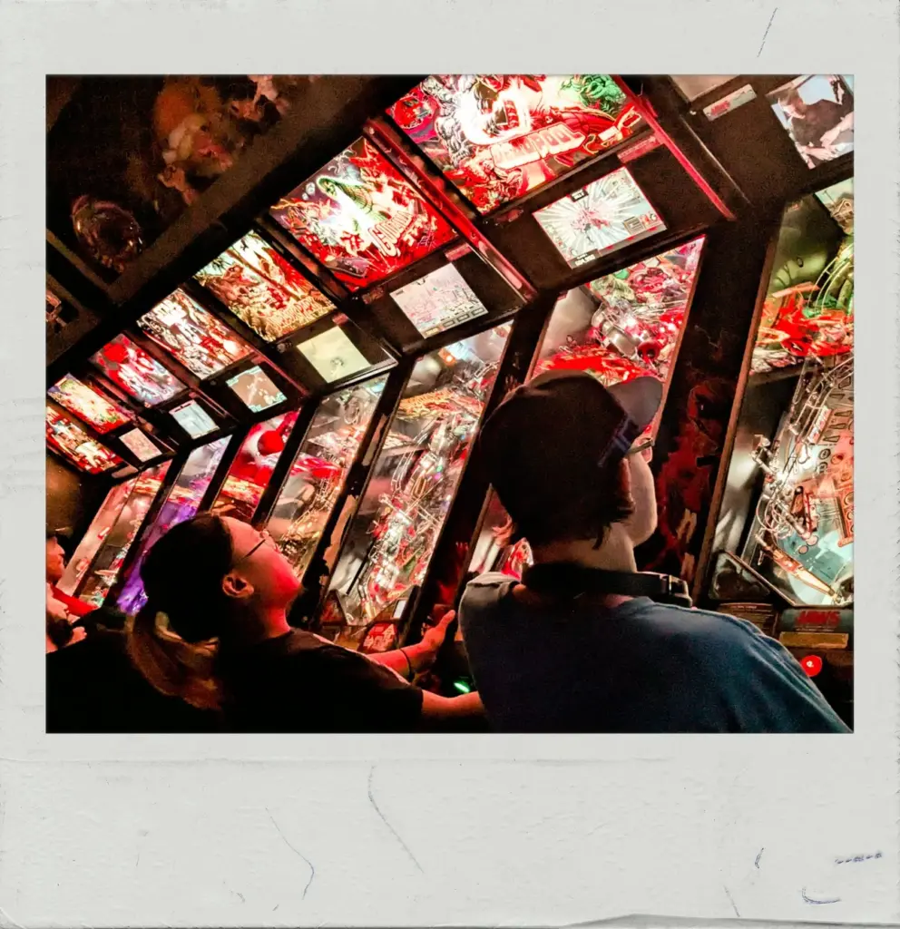 People playing a pinball machine at FreePlay Toronto