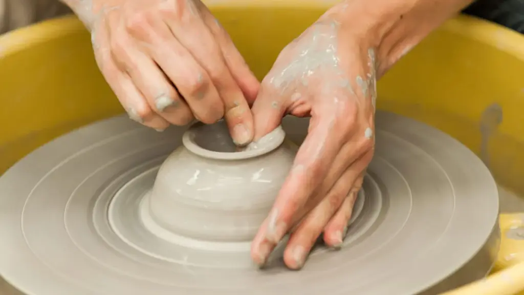 Hands shaping clay on a pottery wheel during a Gardiner Museum class