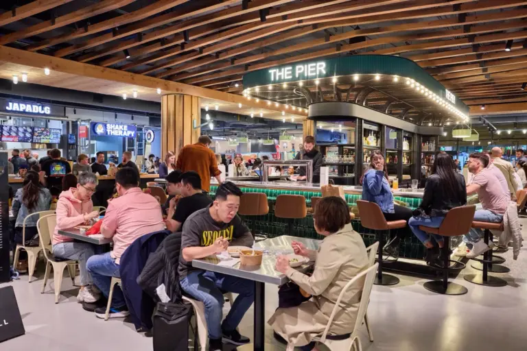 People eating at common tables inside Wellington Market at The Well
