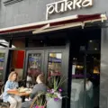 Two women dining on the flower-filled patio at Pukka on St. Clair West in Toronto