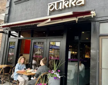 Two women dining on the flower-filled patio at Pukka on St. Clair West in Toronto