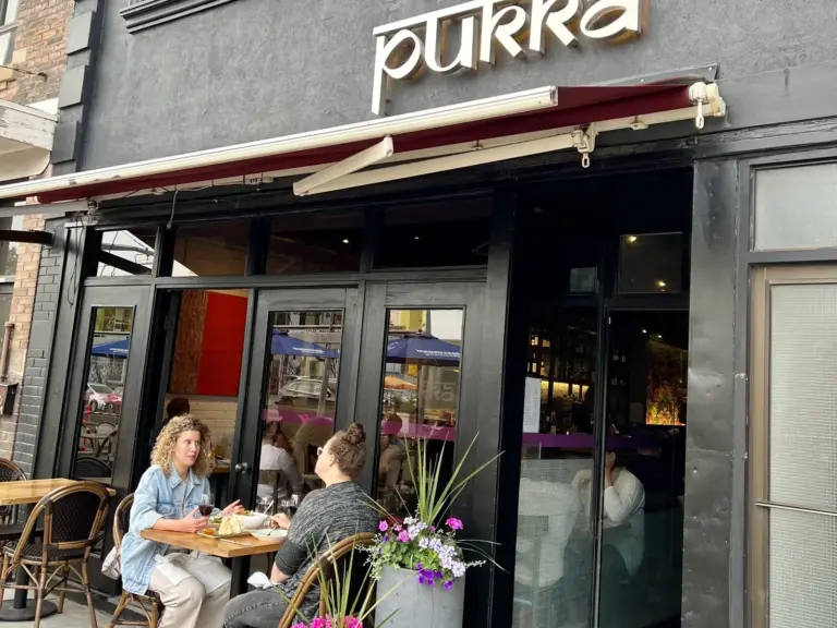 Two women dining on the flower-filled patio at Pukka on St. Clair West in Toronto