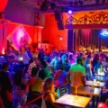 A large crowd gathers around the dance floor inside the brightly lit Lula Lounge.